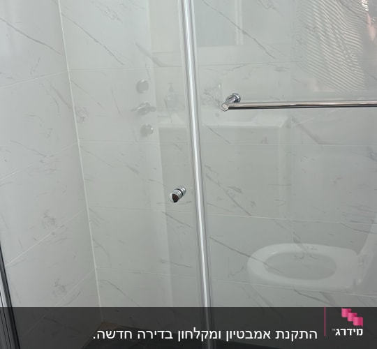 מקלחון עם דלת זכוכית ורצפת אריחים אפורה